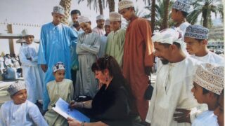 Kunstenares Tonny Holsbergen omringd door nieuwsgierige kijkers in Oman.